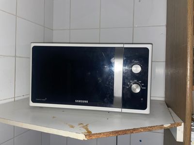 un micro-ondes posé sur une étagère dans un coin de la pièce