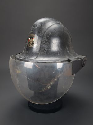 un vieux casque surmonté d’un autre casque, posé sur une surface noire