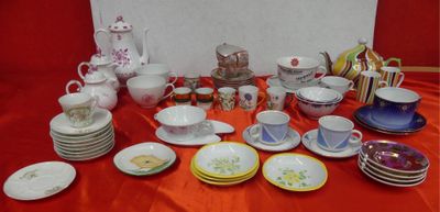 many plates and cups on a table with a red table cloth