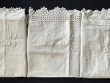 three white linen napkins with embroidered monograms on them