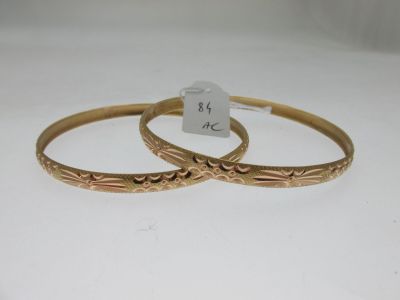 a pair of gold bangles with engraved designs on them