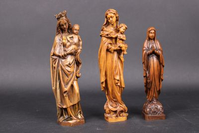 trois statues en bois représentant Jésus, Marie et Jésus sur fond noir