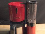 une cafetière rouge posée sur une table en bois
