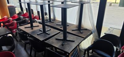 many tables and chairs in a restaurant with a view of the street