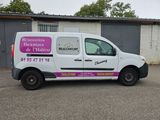 une camionnette garée sur un parking, avec un immeuble en arrière-plan