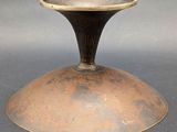 an old bronze vase with a metal base on a gray surface