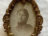 an old picture of a woman in a gold frame