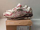 a close up of a pair of pink and white sneakers on a box
