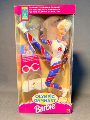 une poupée dans la boîte d'une poupée Barbie contenant une paire de ciseaux