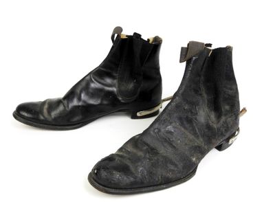 une paire de bottes en cuir noir posées sur une surface blanche, sur fond blanc