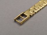 an image of a close up of a gold bracelet on a gray surface