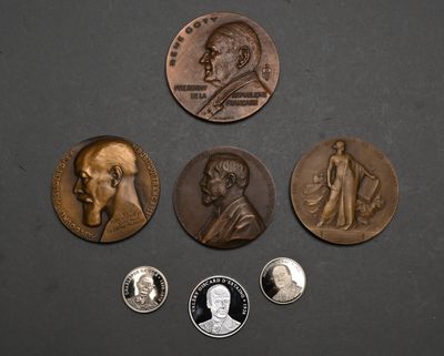 On voit plusieurs pièces de monnaie posées sur une surface noire, dont l'une porte le portrait d'un homme.