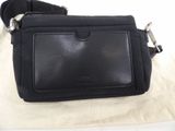 black leather cross body bag with metal buckles on a white surface