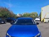 une voiture bleue garée dans un parking à côté d'un bâtiment