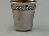 an old silver cup sitting on top of a table next to a white wall