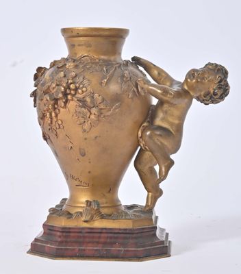 un vase en or sur lequel est représenté un garçon tenant une grappe de raisin