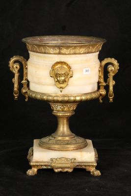 a gold and white urn with a lion head on it