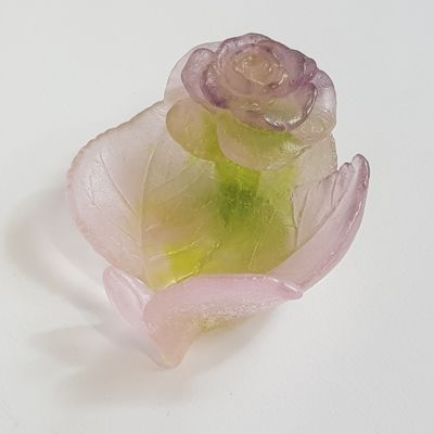 une fleur rose posée sur une surface blanche