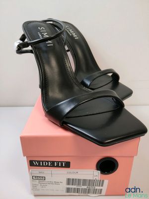 un gros plan sur une paire de chaussures noires posées sur une boîte rose