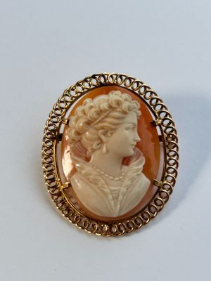 un gros plan sur une broche représentant une femme portant un collier