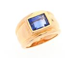 gros plan d'une bague en or avec une pierre bleue