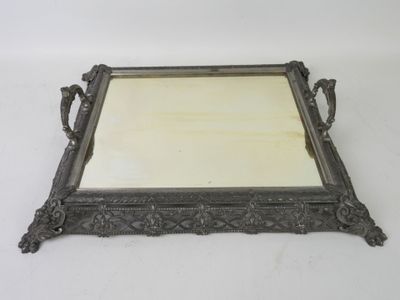 an ornate silver tray with a mirror on it on a white surface
