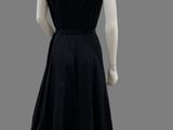 the back of a black dress with a white collared neckline