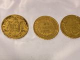 three gold coins sitting next to each other on a white surface