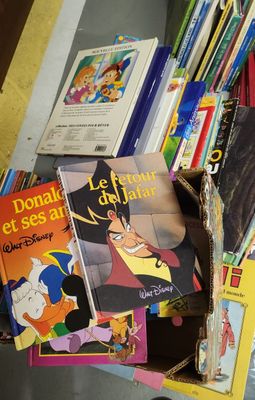 une pile de livres posée par terre, à côté d'une pile de livres pour enfants