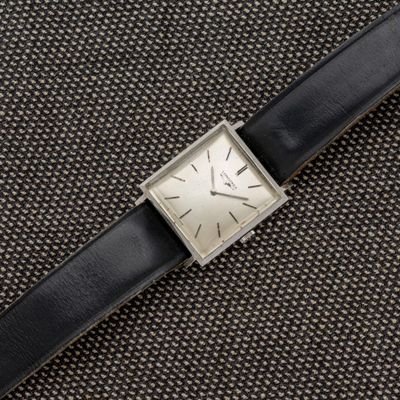 un gros plan d'une montre avec un bracelet noir posée sur une surface noire