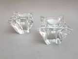 une paire de bougeoirs en verre transparent posés sur une surface blanche