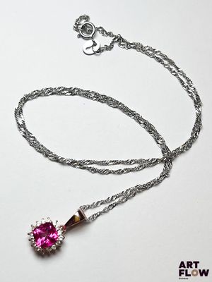 collier avec une pierre rose et une chaîne en argent sur fond blanc