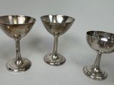 three silver goblets sitting next to each other on a table