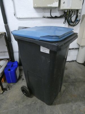 a black trash can with a blue lid in a garage
