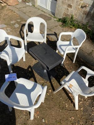 several white plastic chairs and a table in a circle on the ground