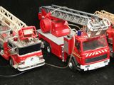 Plusieurs camions de pompiers miniatures sont alignés sur une surface noire