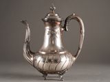 a silver tea pot on a stand on a gray surface