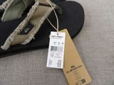 a tag on a pair of flip flops on a bed