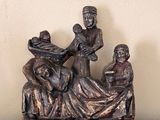 une figurine représentant trois personnes assises sur un lit