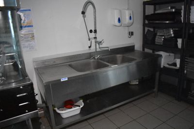 un évier en acier inoxydable dans une cuisine, avec un robinet posé sur le plan de travail