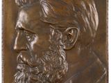 a close up of a bronze plaque of a bearded man