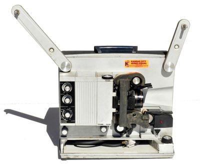 un vieux projecteur de cinéma posé sur une table blanche