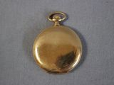 une image représentant une montre de poche en or posée sur un tissu bleu