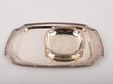 un plateau en argent muni d'une poignée en argent, posé sur une table blanche