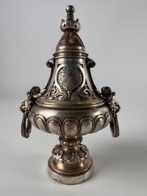 an antique silverplated urn with a bird on top of it