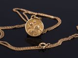 a close up of a gold coin on a chain on a black surface