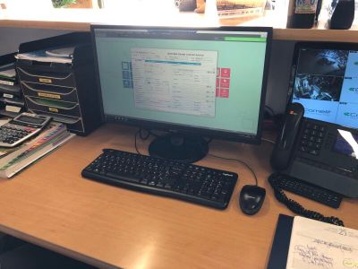 un bureau sur lequel se trouvent un écran d'ordinateur, un clavier, un téléphone et d'autres objets
