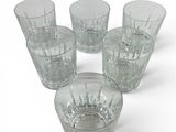 six verres à pied en verre transparent posés sur une surface blanche