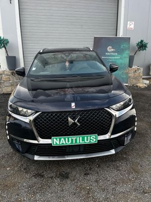 the front end of a black car parked in front of a garage