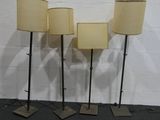 trois lampes posées sur un pied noir, avec un mur blanc en arrière-plan